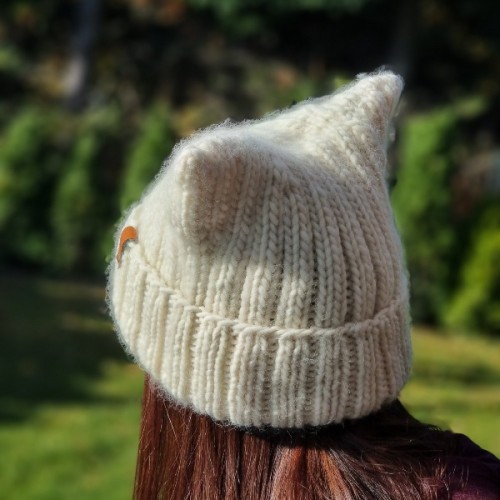 Dziewczynka w robionej na drutach czapce Kitty, ujęcie z boku, prezentacja gotowego projektu, Mila Druciarnia