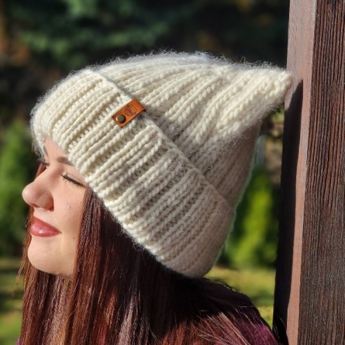 Biała czapka robiona na drutach według wzoru Czapa Kitty by Prezesowa, profilowe ujęcie modelki, Mila Druciarnia